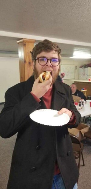 Youth enjoying hot dog during church activity in fellowship hall