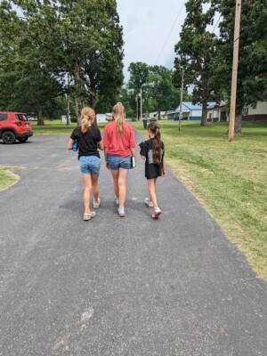 Three girls holding bibles walking down path at Grand Lake Baptist Assembly during children's camp