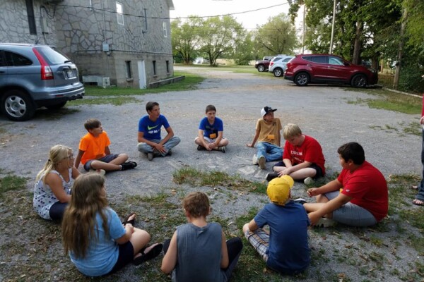 Kids in a group circle for class on church grounds