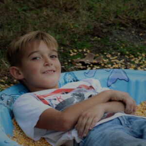 Kid relaxing in plastic pool filed with corn